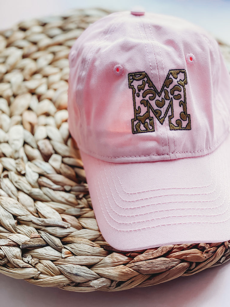 a light pink hat with leopard print single letter M embroidered in gold and black